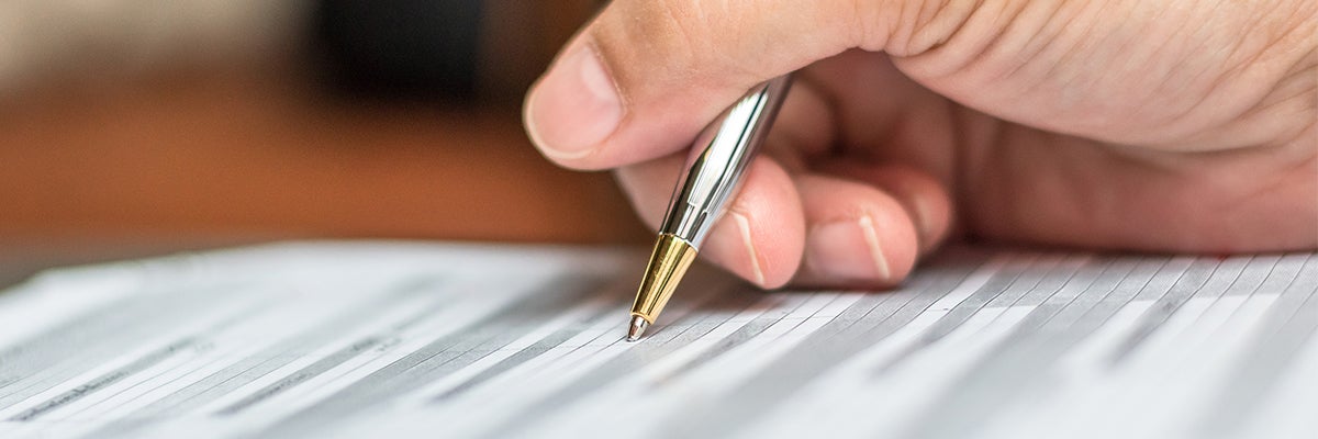 Close up shot of a person's hand holding a pen they are using to file out a form