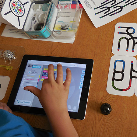 A child programs an Ozobot using the touch screen on a tablet