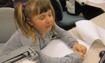 Blind girl reading braille at a desk