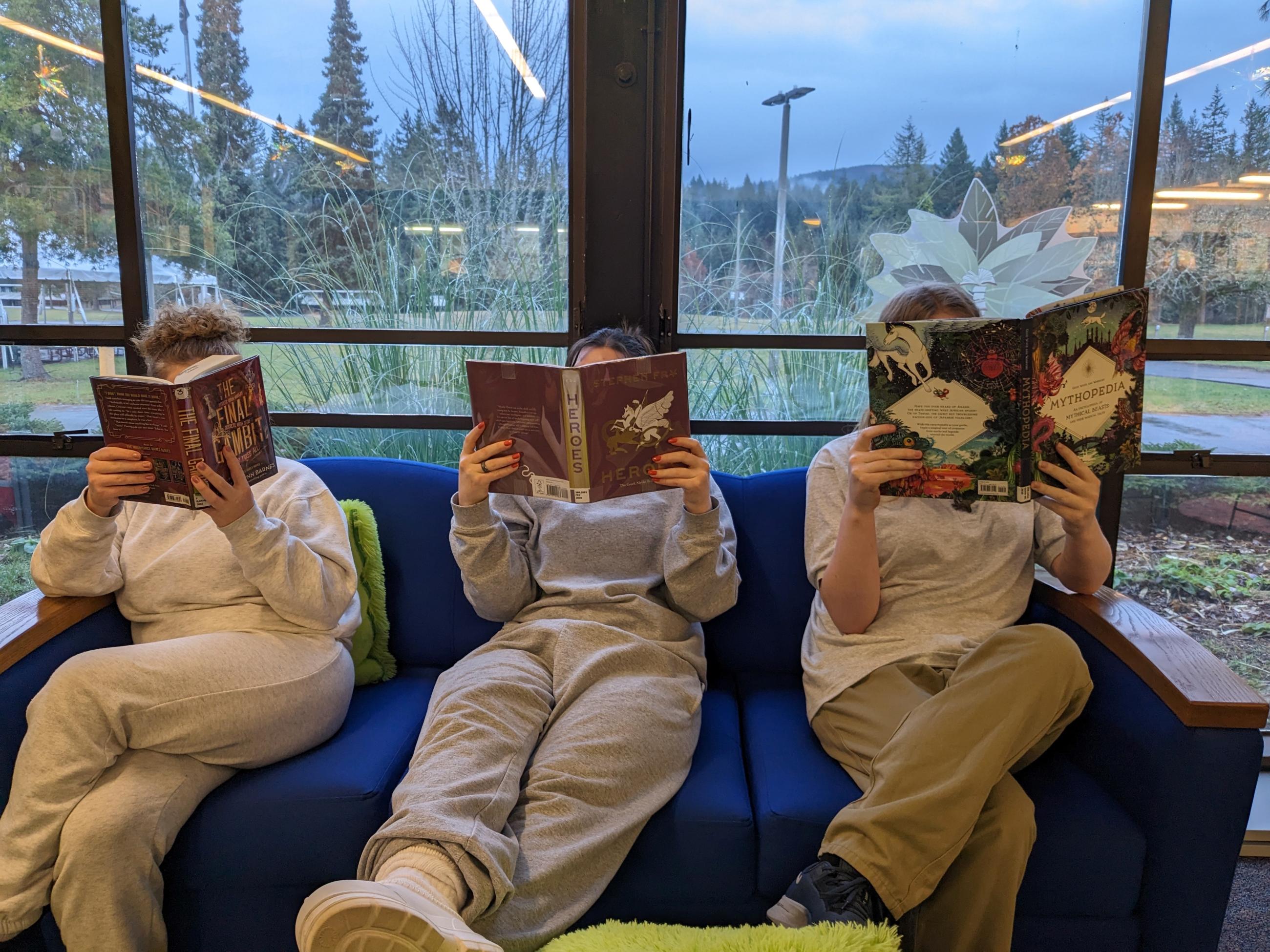 Individuals sitting on a couch while reading