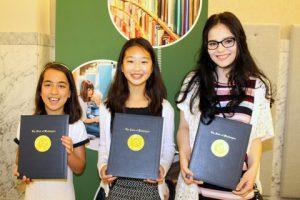 Three young girls smiling and holding a certificate