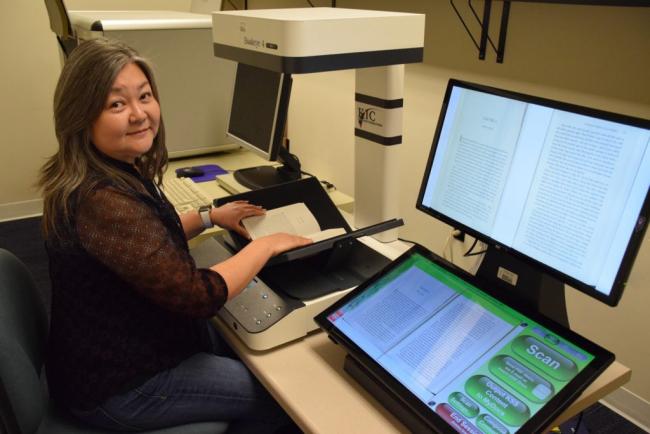 Braille department volunteer working a KIC Bookeye 4 scanner, on which users can quickly and easily convert print books into digital text. The text files are then converted into electronic braille files and sent to braille transcribers, who then use them to create braille books (Photo: Washington Talking Book & Braille Library).