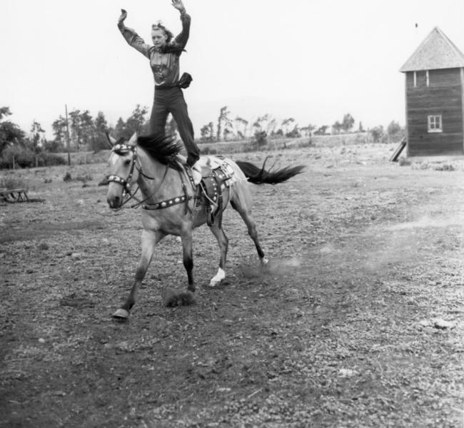 Woman riding a horse while she is standing up