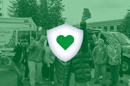 A group of volunteers gather after a successful event. An icon of a shield with a green heart inside is overlaid.