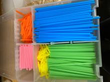 Straws of various sizes and colors grouped in a tray